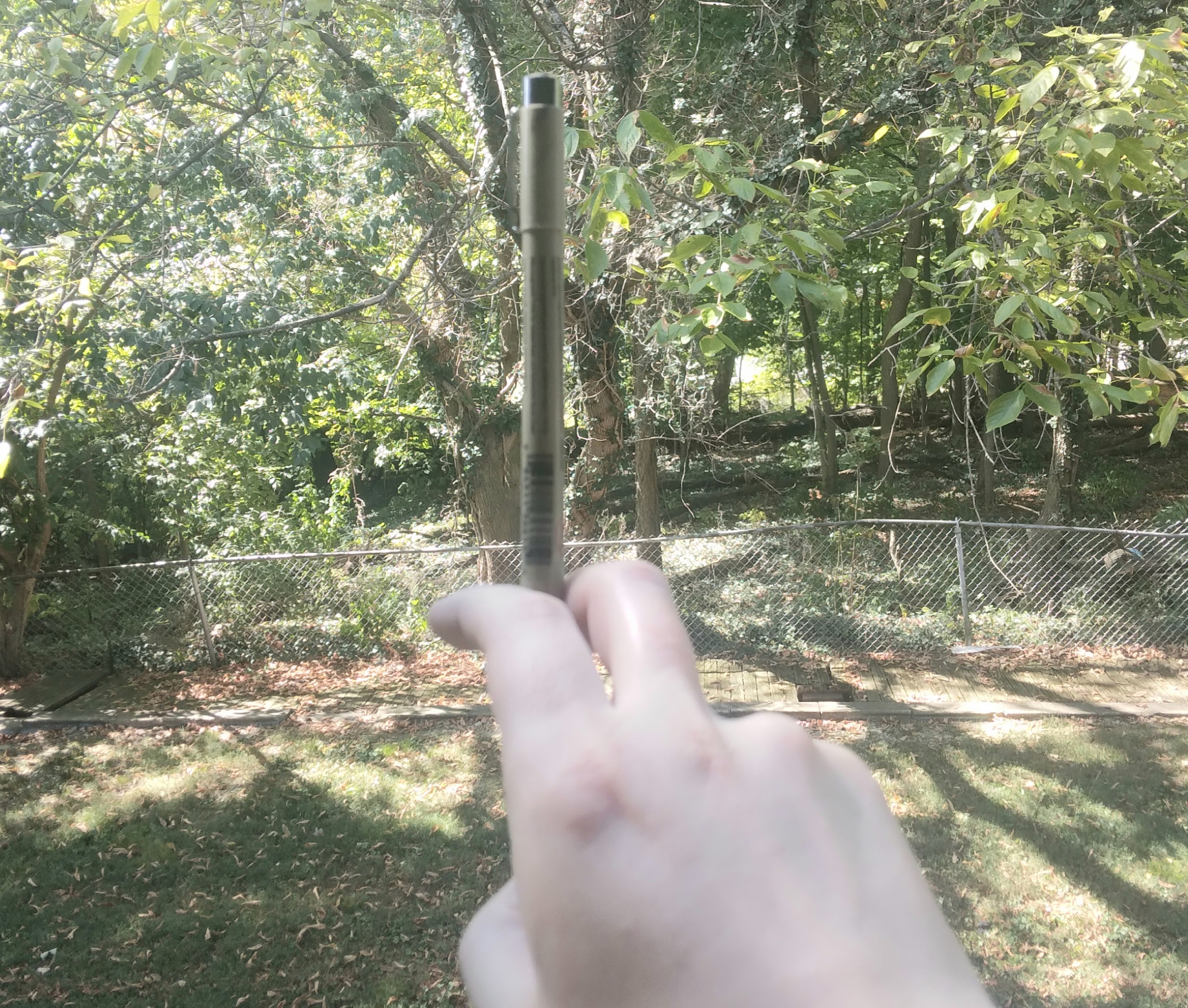 Photo of the tip of a pen being held between the index and middle fingers of a person's hand